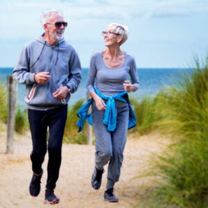 two older joggers running on beach path