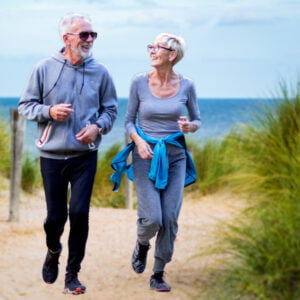 two older joggers running on beach path